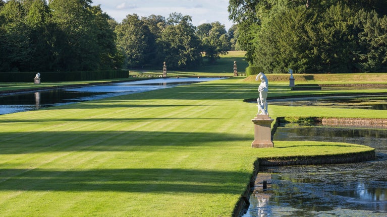 Statues displayed on the lawn beside ponds at Fountains Abbey and Studley Royal Water Garden, North Yorkshire.